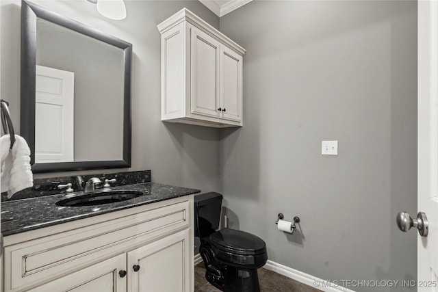 half bath with toilet, baseboards, and vanity