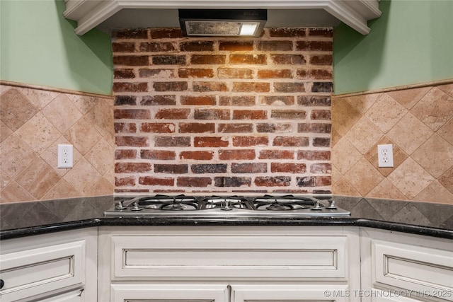 kitchen with stainless steel gas cooktop, white cabinets, and wainscoting