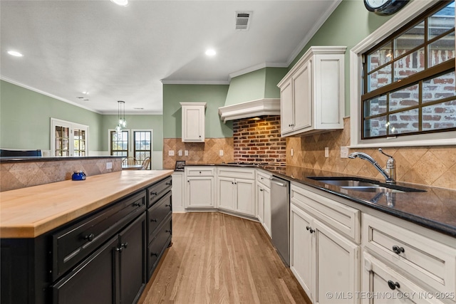 kitchen with visible vents, white cabinets, dishwasher, wood counters, and a sink