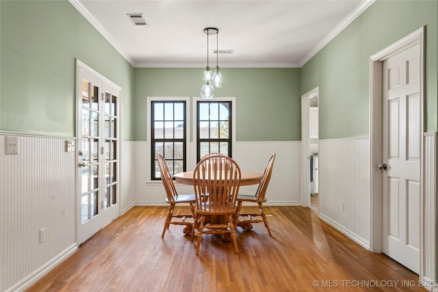 dining room featuring a wainscoted wall, visible vents, and wood finished floors