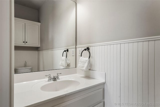 bathroom with a wainscoted wall, toilet, and vanity