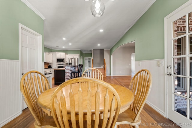 dining space with a wainscoted wall, light wood-type flooring, and crown molding