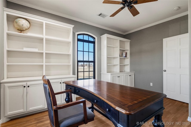 office area with light wood-type flooring, ceiling fan, visible vents, and ornamental molding