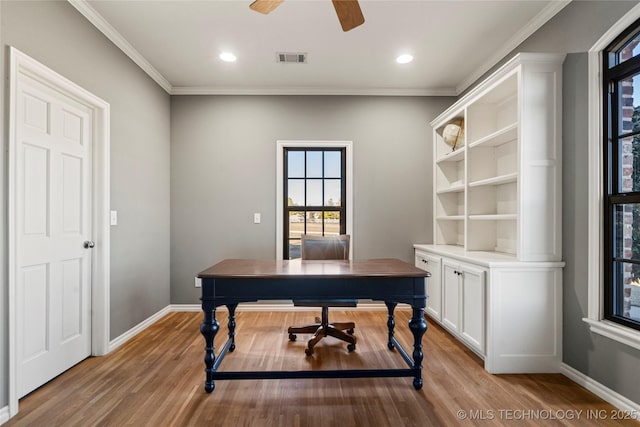 home office with ornamental molding, light wood-type flooring, visible vents, and baseboards