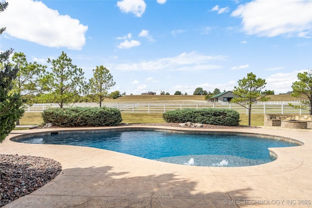 pool featuring a rural view, a patio area, and fence