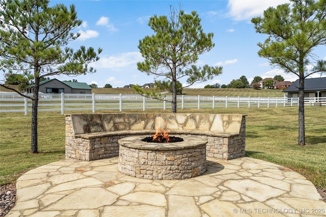 view of patio with an outdoor fire pit, a rural view, and fence