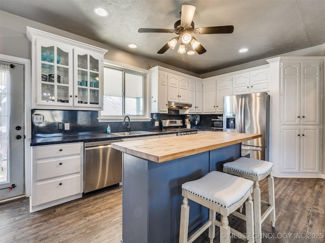 kitchen with a breakfast bar, dark wood-style flooring, appliances with stainless steel finishes, a sink, and wood counters