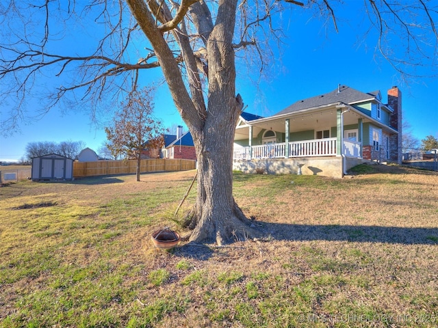 exterior space with an outbuilding, covered porch, fence, a lawn, and a storage unit