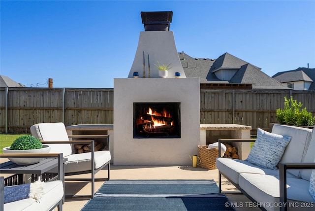 view of patio / terrace with an outdoor living space with a fireplace and fence