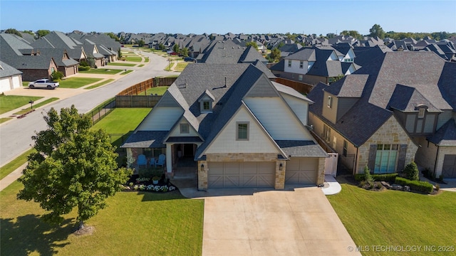 view of front of home featuring stone siding, a residential view, a front lawn, and fence