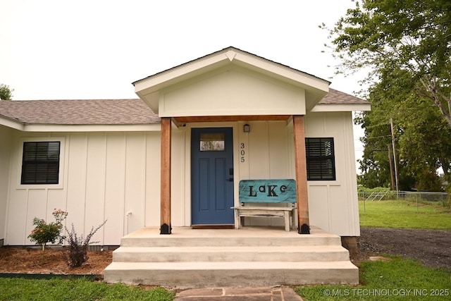 doorway to property featuring a shingled roof, fence, and board and batten siding