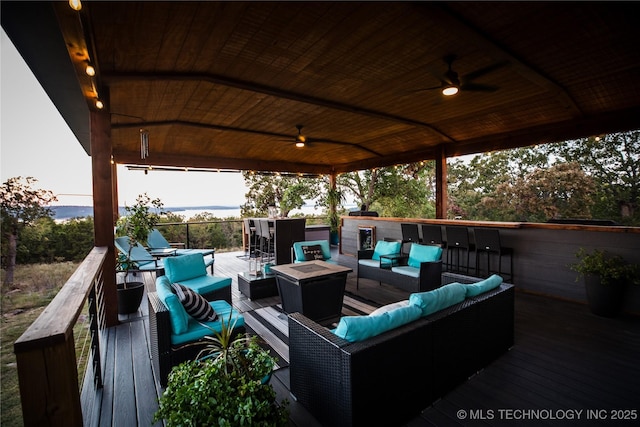 deck featuring a ceiling fan, an outdoor living space with a fire pit, and a gazebo