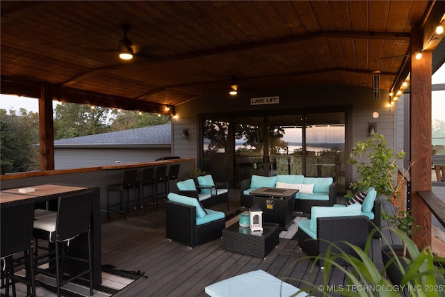 deck at dusk with outdoor lounge area and outdoor dry bar