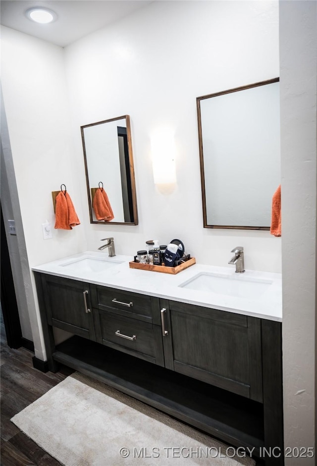 full bath featuring wood finished floors, a sink, and double vanity