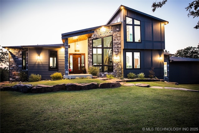 exterior space featuring board and batten siding, stone siding, and a lawn