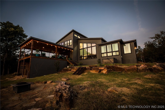 back of property with a lawn, a wooden deck, and stairs