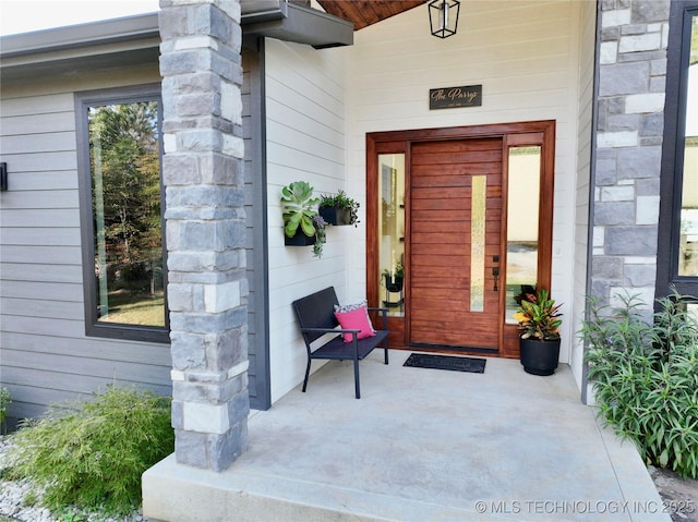 entrance to property with stone siding and a porch