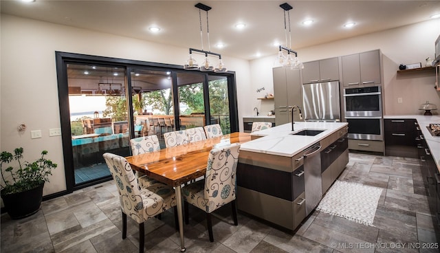 kitchen with a center island with sink, modern cabinets, stainless steel appliances, gray cabinetry, and a sink