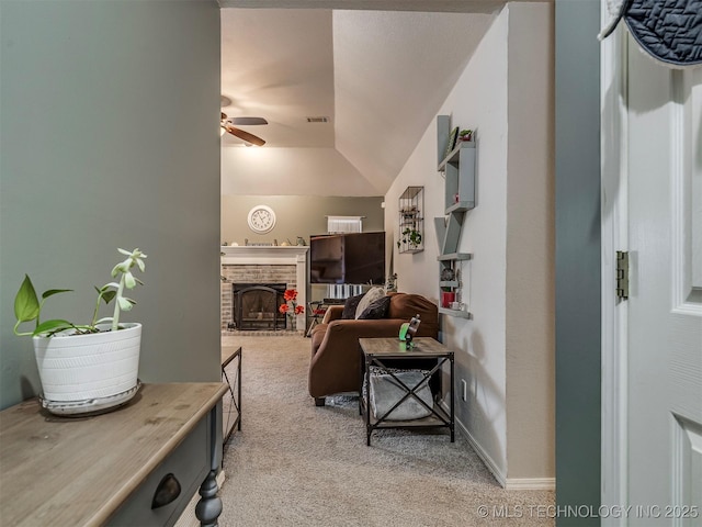 living area with lofted ceiling, light colored carpet, a fireplace, visible vents, and a ceiling fan