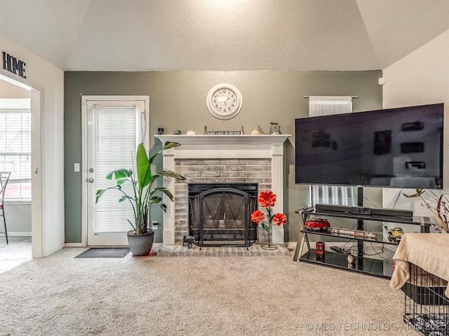 carpeted living area with lofted ceiling, a fireplace, and plenty of natural light