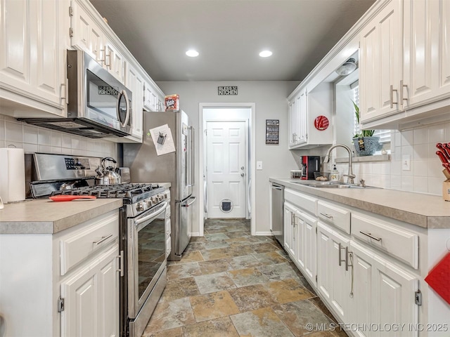 kitchen with stone tile flooring, stainless steel appliances, a sink, and light countertops