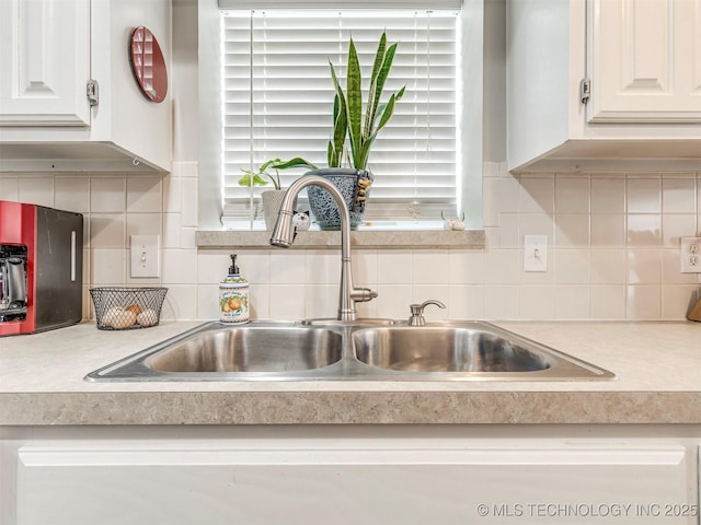 details featuring white cabinets, light countertops, a sink, and backsplash