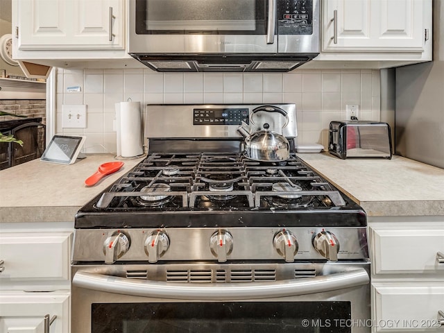 kitchen featuring stainless steel appliances, decorative backsplash, light countertops, and white cabinets