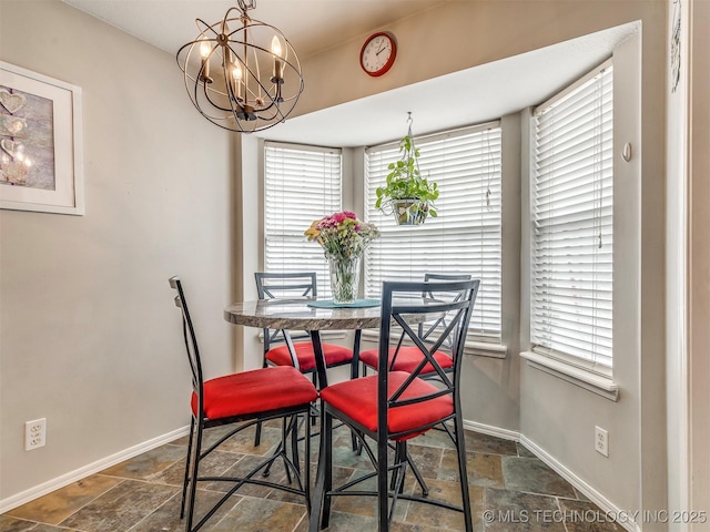 dining space featuring a notable chandelier, stone finish floor, and baseboards