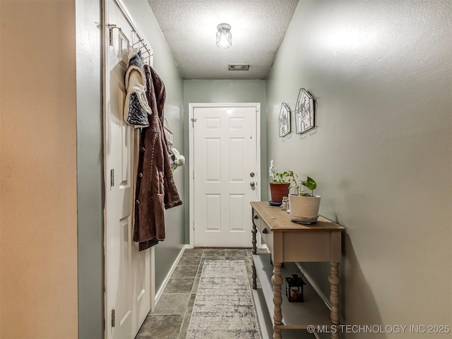 doorway to outside with baseboards, visible vents, and a textured ceiling