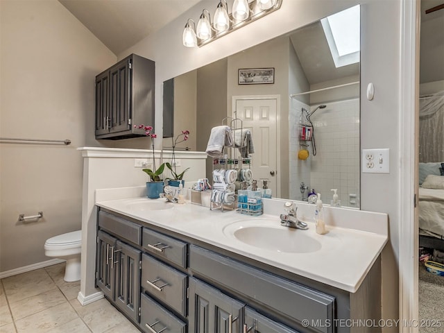 bathroom with toilet, vaulted ceiling with skylight, double vanity, and a sink