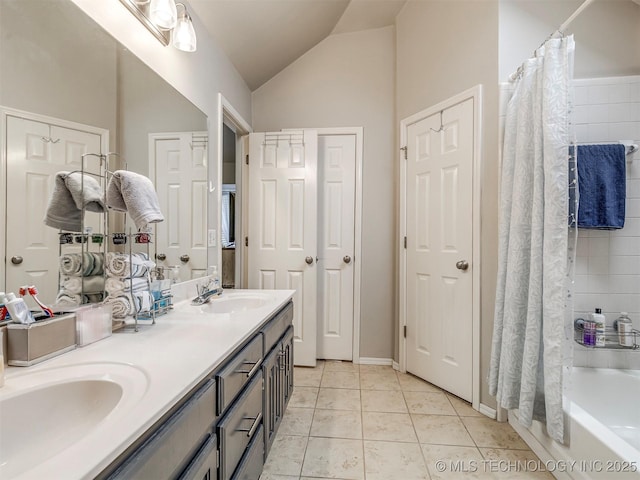 bathroom featuring lofted ceiling, double vanity, a sink, and tile patterned floors