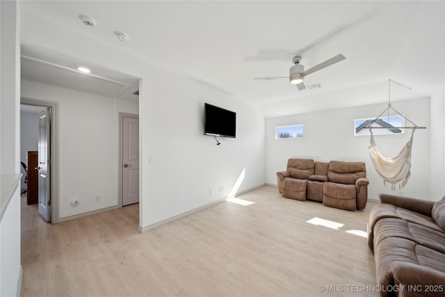 living area featuring attic access, light wood-style floors, baseboards, and ceiling fan