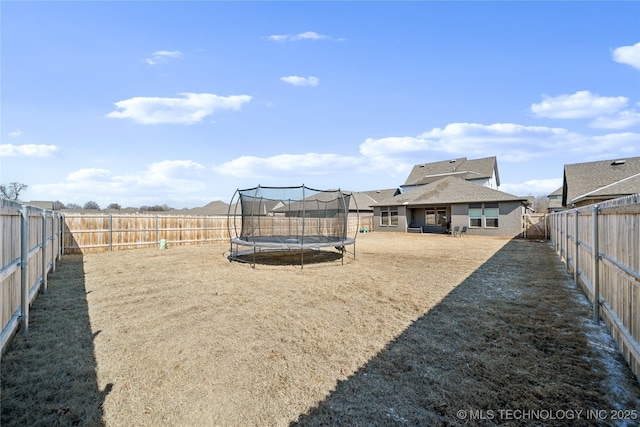 view of yard featuring a trampoline and a fenced backyard