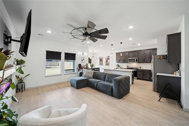 living area featuring light wood-type flooring, visible vents, and recessed lighting