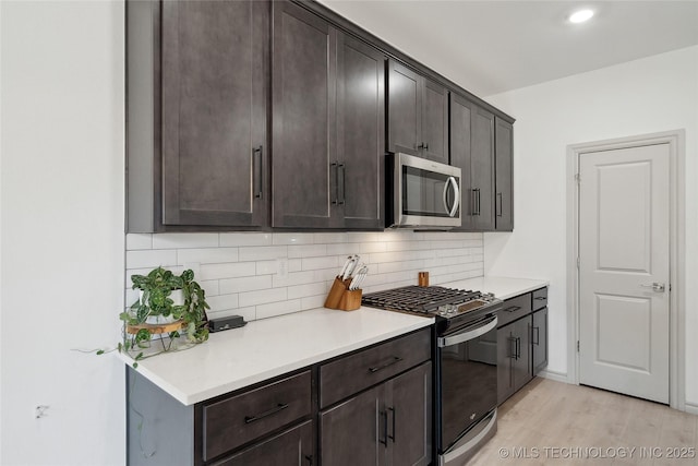 kitchen with dark brown cabinets, tasteful backsplash, stainless steel microwave, and range with gas cooktop