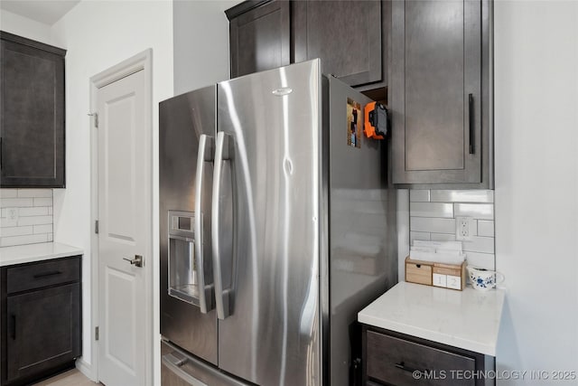 kitchen featuring stainless steel fridge, decorative backsplash, and dark brown cabinets