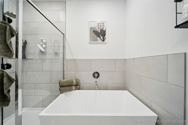 full bath featuring a tub to relax in and tile walls