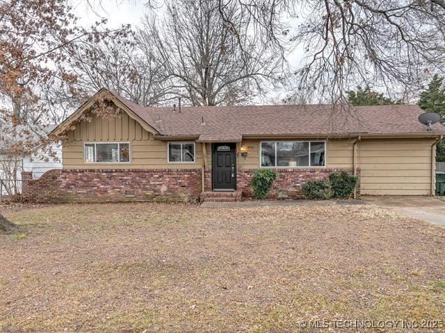 ranch-style house featuring board and batten siding, brick siding, and fence