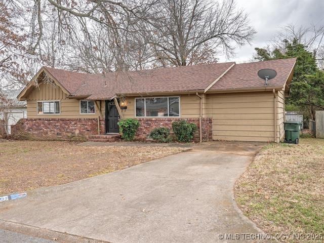 single story home featuring roof with shingles, a front yard, fence, and brick siding