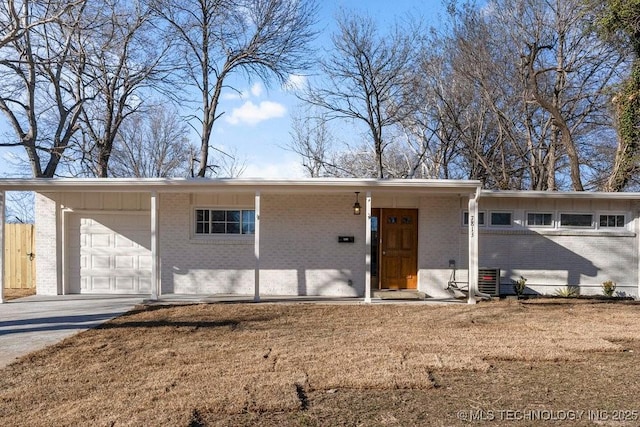 view of front facade with concrete driveway, an attached garage, fence, and brick siding