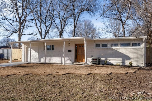 ranch-style home featuring brick siding, central AC, an attached garage, and fence