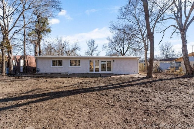 rear view of property with fence and brick siding