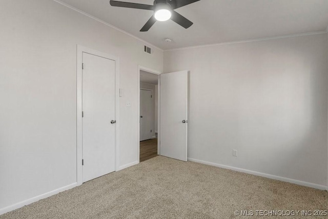 unfurnished bedroom with visible vents, ornamental molding, a ceiling fan, carpet, and baseboards