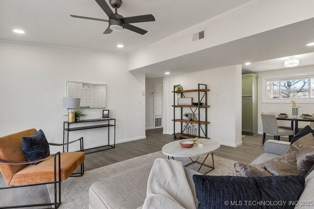 living room featuring visible vents, wood finished floors, baseboards, and ornamental molding