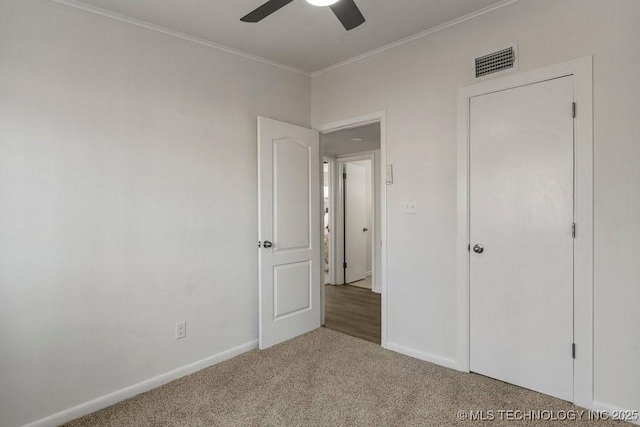 unfurnished bedroom featuring visible vents, baseboards, carpet flooring, and crown molding