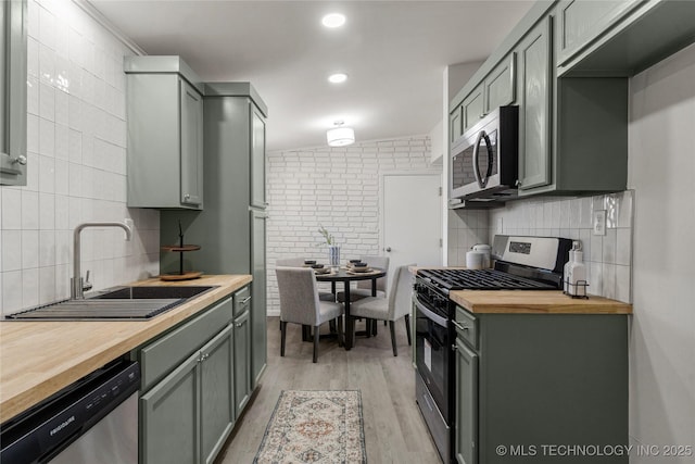 kitchen with light wood-style flooring, a sink, wood counters, tasteful backsplash, and stainless steel appliances