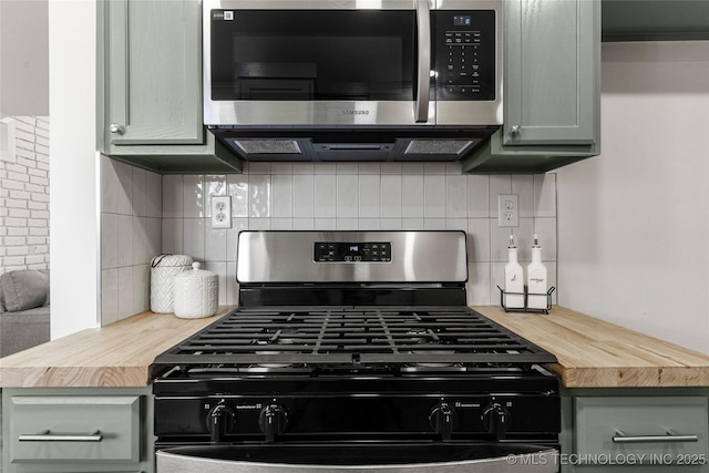 kitchen featuring tasteful backsplash, gray cabinets, appliances with stainless steel finishes, and butcher block counters