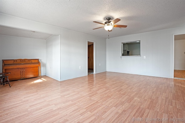 spare room with light wood-style floors, ceiling fan, and a textured ceiling