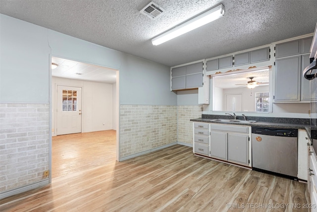 kitchen featuring dark countertops, light wood finished floors, and stainless steel dishwasher