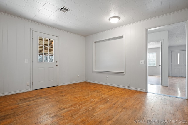 spare room featuring baseboards, hardwood / wood-style floors, visible vents, and crown molding